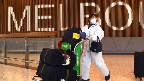 Une voyageuse porte une combinaison personnelle de protection contre le Covid-19, le 29 novembre 2021, à l'aéroport de Melbourne en Australie, alors que les premiers cas de contamination au variant Omicron du virus ont été enregistrés dans le pays.