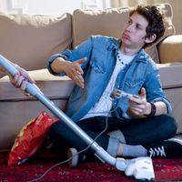 Adolescent contrarié d'interrompre son jeu vidéo quand sa mère passe l'aspirateur