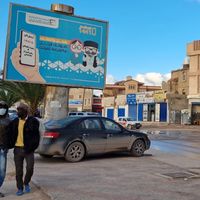 Des passants à Tripoli devant une affiche invitant à s'inscrire sur les listes électorales pour le scrutin du 24 décembre