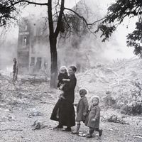 Une mère et ses enfants au milieu des décombres fumants de leur ville après un bombardement nazi