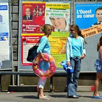 Des vacanciers marchent devant des panneaux électoraux à Saint-Malo, le 12 juin 2004 à l'occasion des élections européennes.