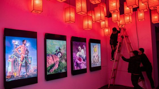 Des employés préparent l'une des premières expositions physiques de crypto art à Pékin, le 26/03/21 ©AFP - NICOLAS ASFOURI