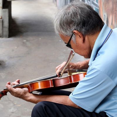 Un homme, d'un certain âge et malvoyant, joue du violon