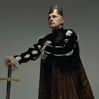 Homme ordinaire portant un costume de roi et un sceptre, le regard au loin