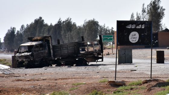Une carcasse de camion gisant derrière la bannière de Dash peinte sur un tableau dans le village de Dibsi Afnan le 11 juin 2017 ©AFP - George Ourfalian