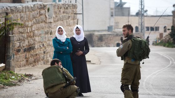Soldats israéliens fouillant les sacs de deux Palestiniennes à Hebron, en Cisjordanie ©AFP - MENAHEM KAHANA