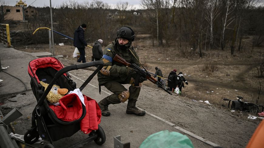 Un soldat ukrainien protège la fuite d'habitants d'Irpin, le 13 mars 2022.