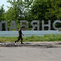 Un militant pro-russe armé, devant le signe "Slavyansk" écrit en ukrainien, à l'est de l'Ukraine, à Slavyansk, en 2014;