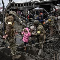 Des Ukrainiens traversent un pont détruit en fuyant la ville d'Irpin, au nord-ouest de Kiev le 05 mars 2022
