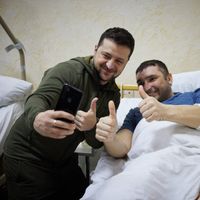 Le président ukrainien Volodymyr Zelensky prend un selfie avec un homme blessé lors d'une visite dans un hôpital militaire dans la région de Kiev