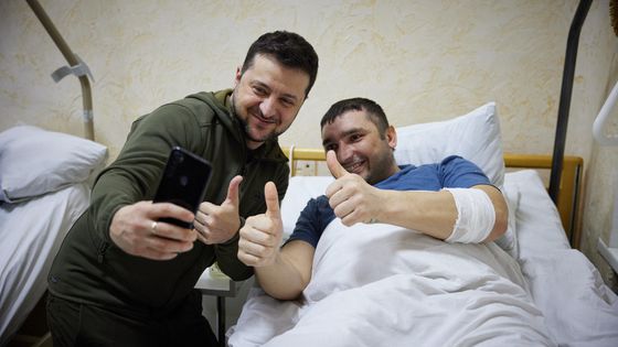 Le président ukrainien Volodymyr Zelensky prend un selfie avec un homme blessé lors d'une visite dans un hôpital militaire dans la région de Kiev ©AFP - UKRAINIAN PRESIDENTIAL PRESS SERVICE / AFP