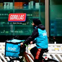 Un livreur passe à vélo devant un entrepôt de livraison urbain Gorillas.