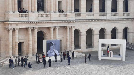 Emmanuel Macron et des élèves du Conservatoire déposent des fleurs au pied du portrait de Michel Bouquet dans la cour d'honneur des Invalides ©Radio France - Benoît Grossin