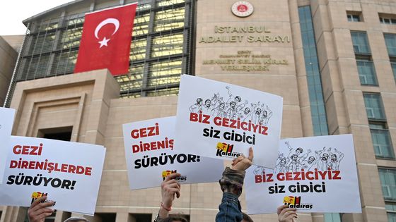 Avocats et défenseurs des droits de l'Homme réunis devant le tribunal pour soutenir Osman Kavala avec des pancartes disant : "La résistance Gezi continue" ©AFP - OZAN KOSE