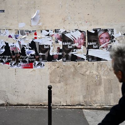 Un passant regarde des affiches de campagne déchirées à Paris le 24 avril 2022 après l'annonce des résultats de l'élection présidentielle française.