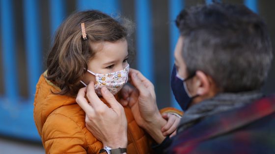 Un père ajustant le masque protecteur de sa fille devant l'école, pendant l'épidémie de Coronavirus ©Getty - Catherine Delahaye