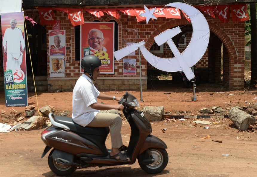 Un scooter passant devant des affiches du parti communiste à Vadakara au Kerala