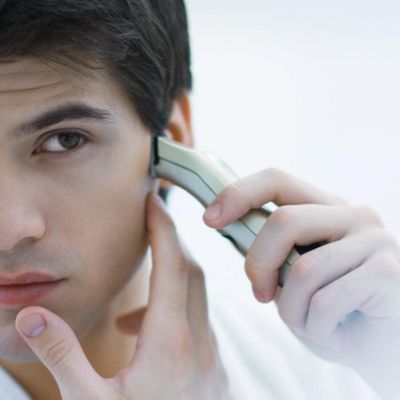 Un homme se rase devant un miroir.