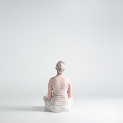 Femme assise de dos les jambes croisées.