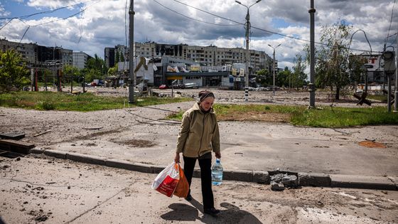 Une femme porte des sacs contenant de la nourriture alors qu'elle marche dans le quartier détruit de Saltivka, au nord de Kharkiv, le 17 mai 2022. ©AFP - Dimitar Dilkoff
