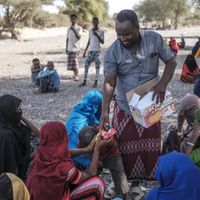 Un homme distribue de la nourriture dans un camp de personnes déplacées dans la région de Semera (Ethiopie) le 15 février 2022