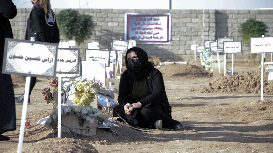 Une femme pleure près d'une tombe lors des funérailles de masse des victimes yézidies du groupe État islamique le 9 décembre 2021