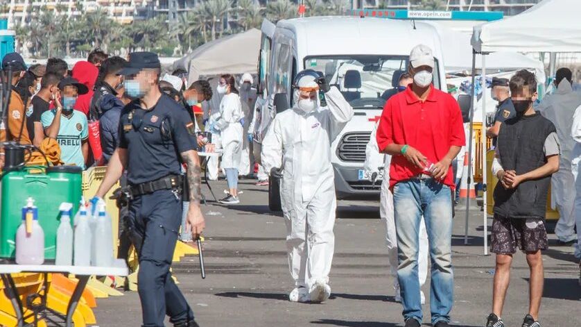 Un policier, un agent de santé et plusieurs immigrés sur la jetée d'Arguineguín, le 18 nov. 2020 à Gran Canaria, Îles Canaries, Espagne.