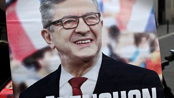 Un militant de La France Insoumise avec une affiche de campagne indiquant "Mélenchon, Premier ministre" devant le siège de LFI à Paris le 3 mai 2022 ©AFP - EMMANUEL DUNAND