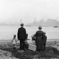 Famille d'immigrants à Ellis Island face à New-York