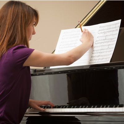 Jeune femme à son piano et travaillant sur une partition