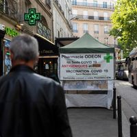 Des passants devant une pharmacie pratiquant des tests antigéniques et PCR, à Paris le 20 juin 2022.