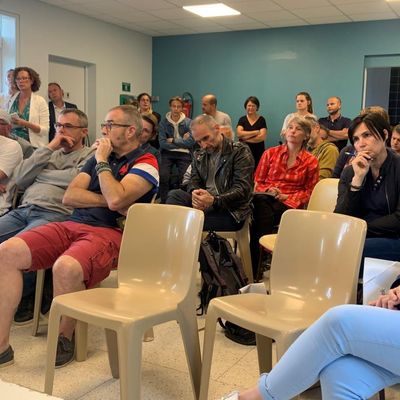 Des parents écoutent le cofondateur du laboratoire ToxSeek expliquer les résultats des analyses des cheveux de leurs enfants, atteints de cancer à la salle des fêtes d'Igoville dans l'Eure (juin 2022).