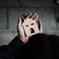 Un homme tient une maison en carton entre les mains.