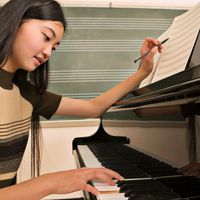 Adolescente au piano et travaillant sur la partition
