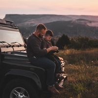 Un père initie son fils à la photographie, au coucher du soleil